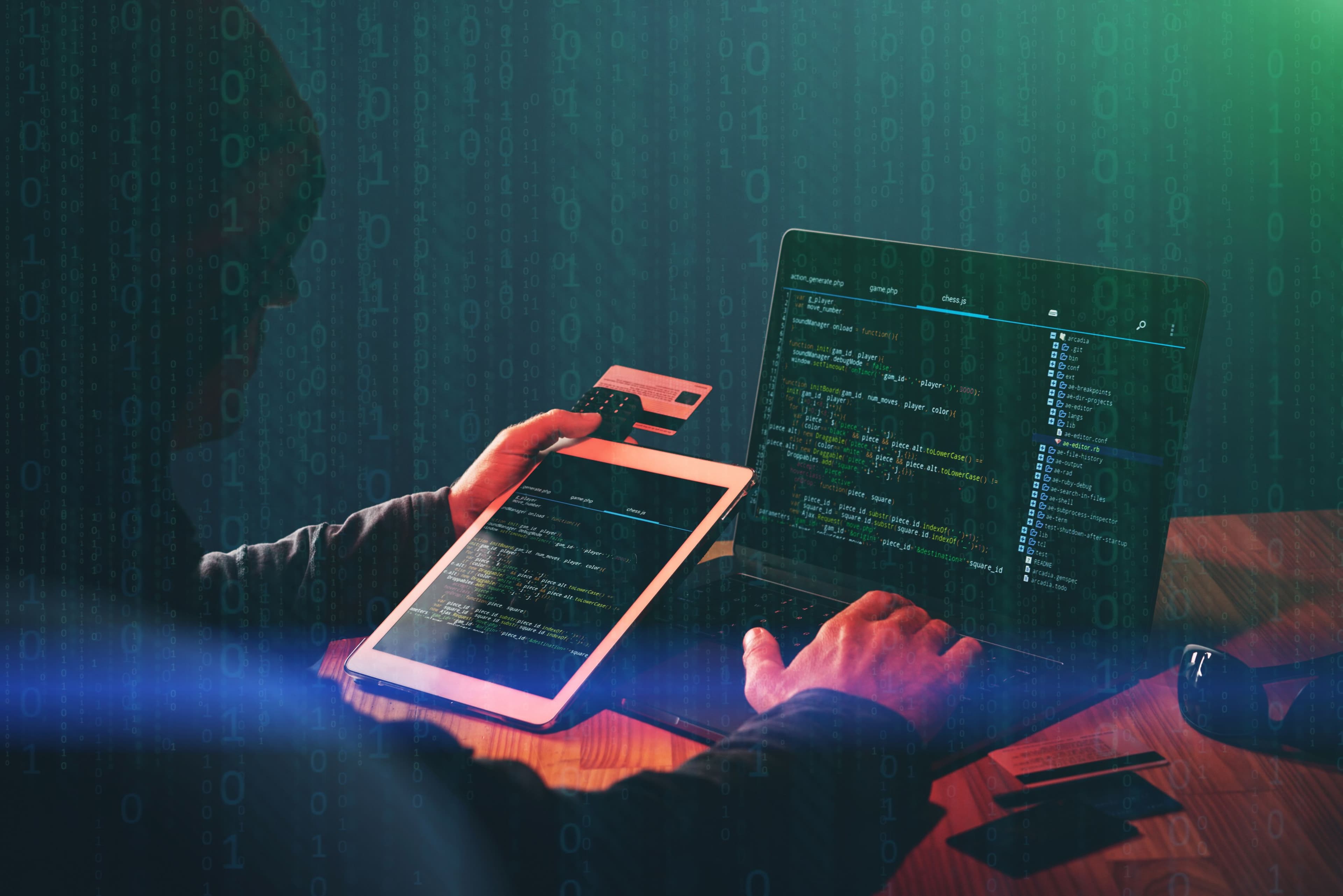 Hacker using an ipad and laptop